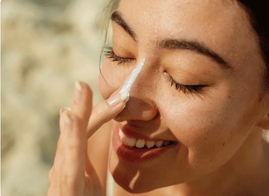 A woman using on of Green People's sunscreens that she saved on with a Green People voucher code