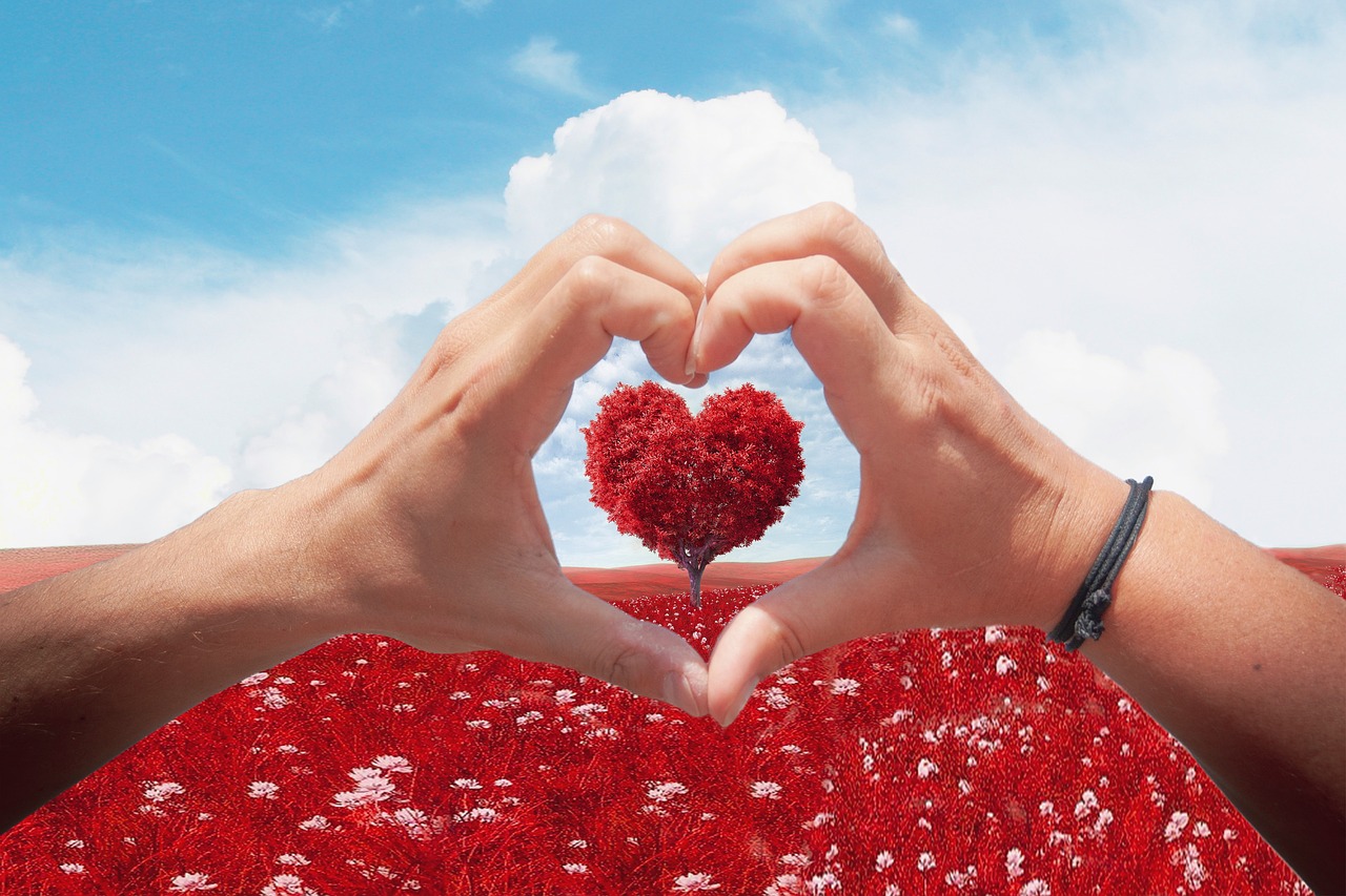 manos formando un corazón rojo con cielo azúl de fondo disponible con ofertas de san valentín