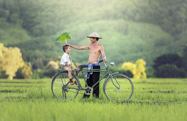 Vater mit seinem Sohn neben einem Fahrrad auf einer Wiese durch den Vatertag Gutschein