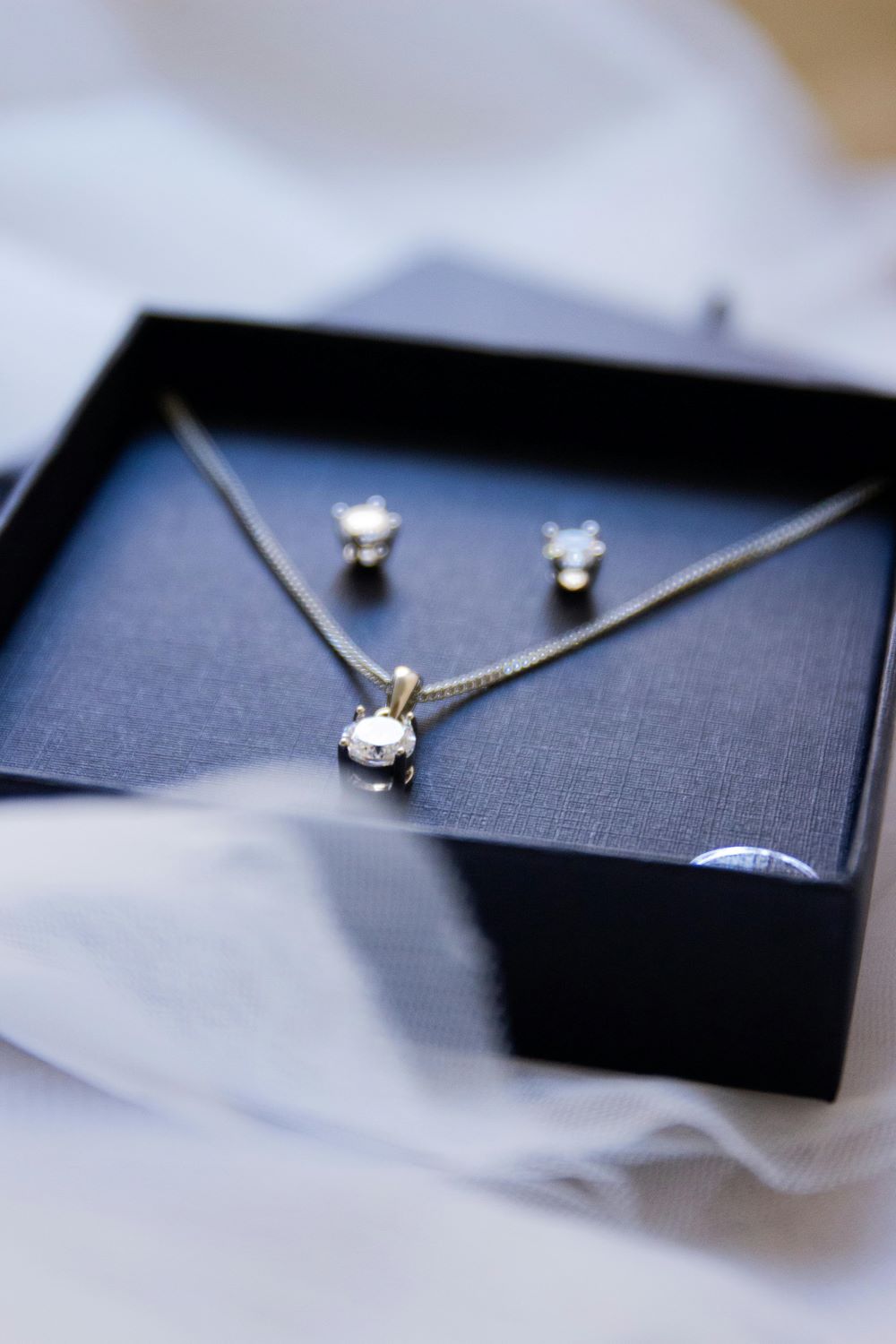 A black jewelry box with a diamond necklace and a pair of diamond earrings.