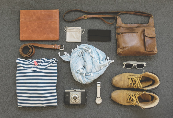 Accesorios de zapatos sobre alfombra de color gris con tres bolsos, móvil y gafas de sol