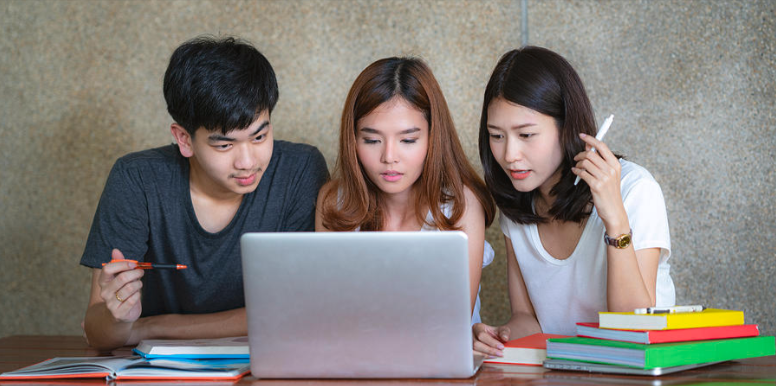 Asian young man and two women sitting pointing at a Dick's Sporting Goods discount code