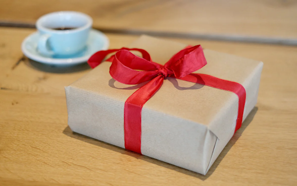 Ein kleines Geschenkpäckchen neben einer kleinen Kaffeetasse