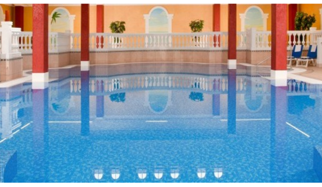 Ein Schwimmbecken mit rötlichen Säulen und weißem Geländer