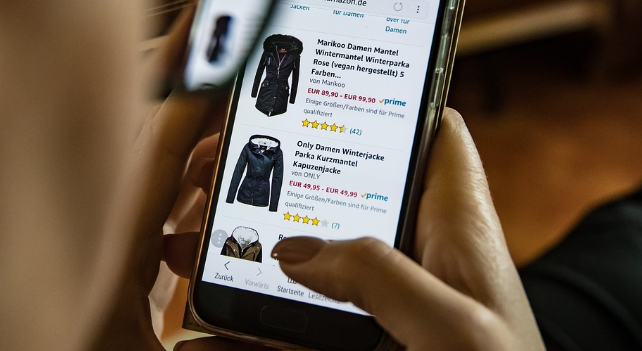 Eine Person mit Smartphone, die sich Bekleidung darauf für den January Sales Gutschein anschaut