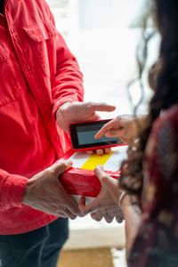 A courier man handing a parcel to a customer who is signing for delivery on a handheld device
