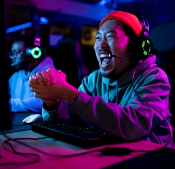 A young man wearing a red beanie and a headset with a miscrophone, sitting infront of a computer