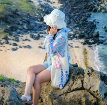 Woman sitting on rocky cliff overlooking scenic beach