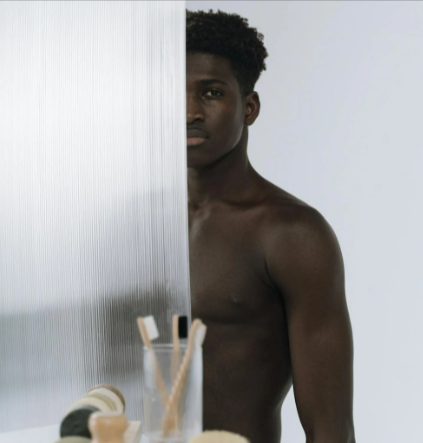 Man behind a shower curtain after grooming himself with Cornerstone products