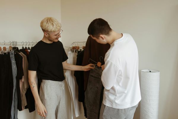 Two men in a clothing store, with one holding up a pair of jeans on a hanger