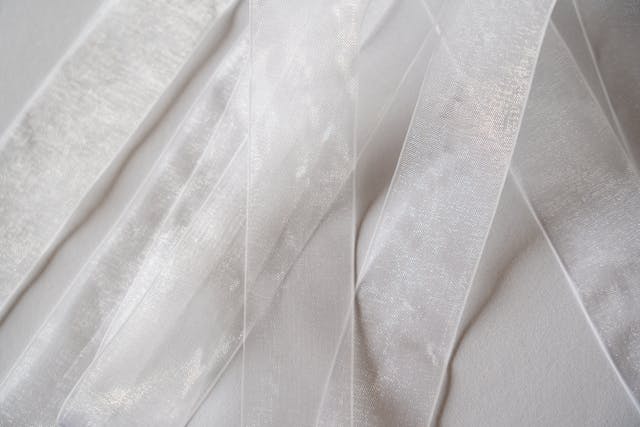 White and grey textile sheer net curtains available for purchase from Woodyatt Curtains.