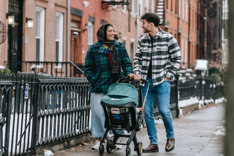 famiglia mentre cammina per strada con il proprio neonato nel passeggino comprato a prezzo conveniente con un coupon STOKKE
