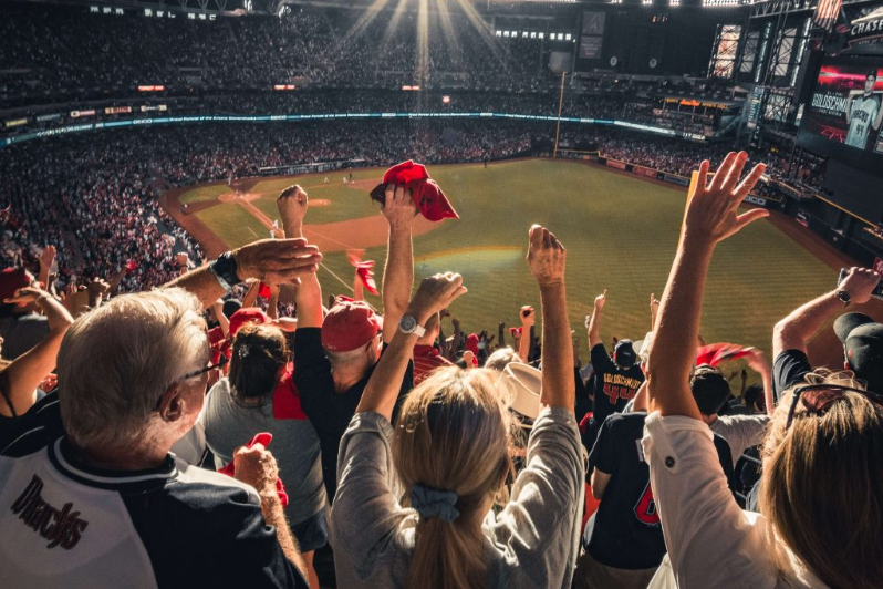 A picture showing fans inside a stadium celebrating with red scarves and hats