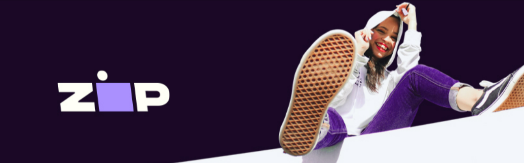 A woman wearing a hoodie is seated on a white block in the purple and white Zip logo.