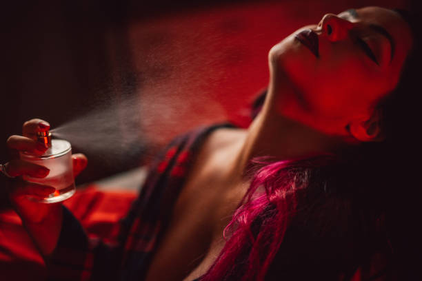 une femme portant une robe rouge entrain de se parfumer. Ce parfums est disponible avec un code promo Frmoda