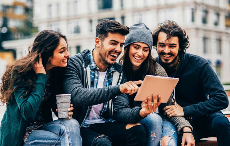 University students gathered around and looking at a tablet screen for a Trip.com discount code from Love Coupons.