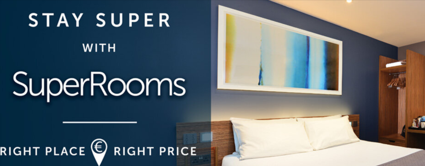 Travelodge UK superroom on display. Bed and small closet and other words can be seen