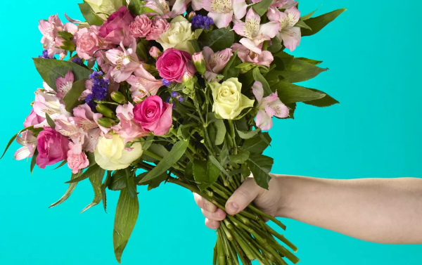 A hand holding a beautiful and colourful flower bouquet