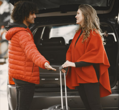 A couple standing by their car, packing luggage for a road trip after booking other trips extras through Holiday Extras.