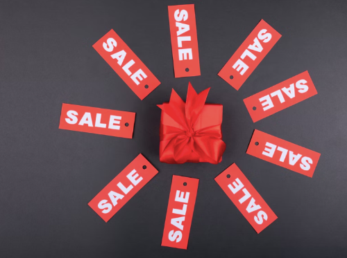 Red and white sale signs circling a gift box 