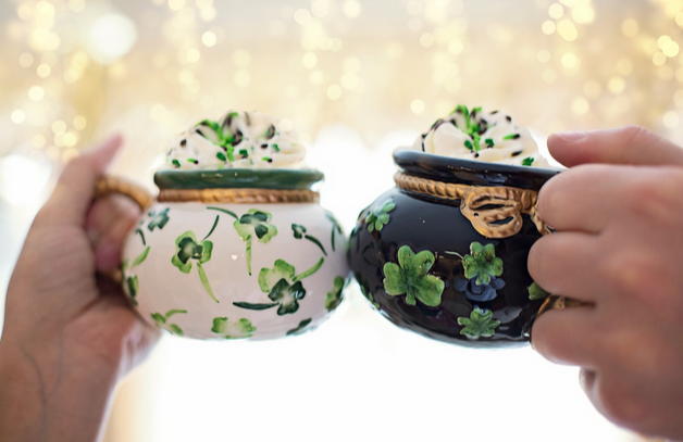 Zwei Hände die mit zwei Krügen mit Kleeblattmustern anstoßen, mit dem St. Patrick's Day Gutscheincode