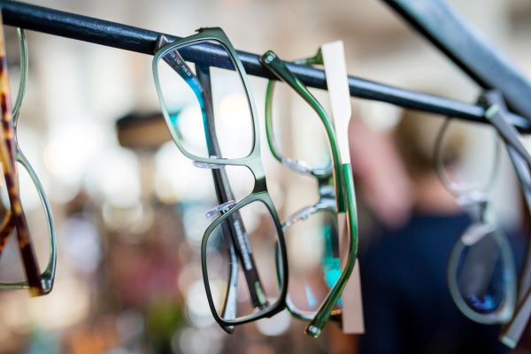 Eyeglasses hanging on a metal bar in an optical store
