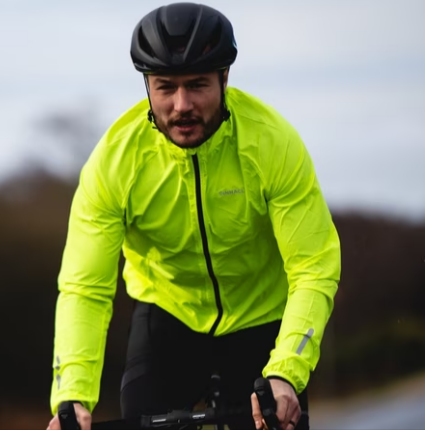 A man cycling with a black bike, helmet, and a lime green jacket available at Evans Cycles