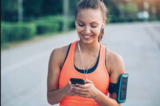 A woman athlete looking at her cellphone for Muscle Nation voucher code