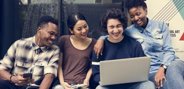 Students sitting outside searching for CAMILLA AND MARC promo code on the laptop