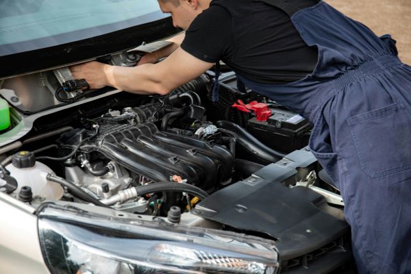 A mechanic perfoming a routuine car maintenance check on the engine compartment