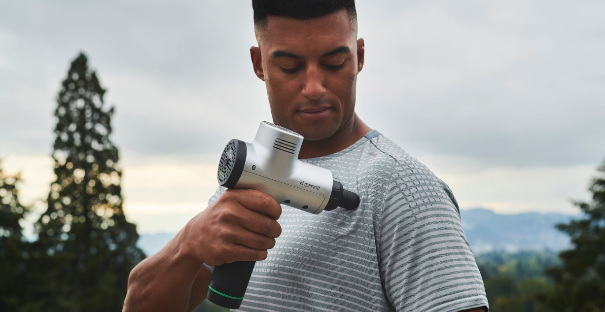 a male person wearing a grey athletic shirt while massaging his shoulder