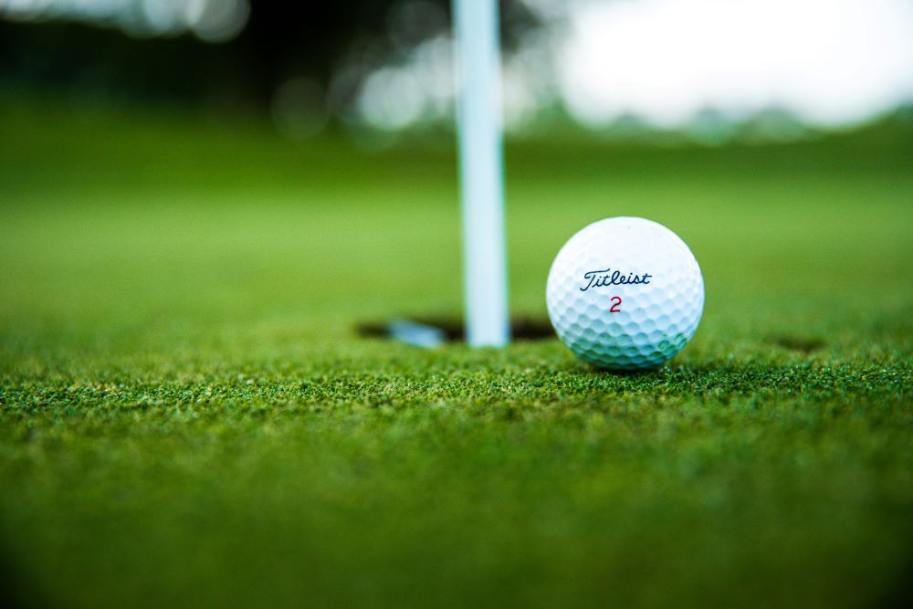 A Titleist golf ball on a green golf field outdoors.