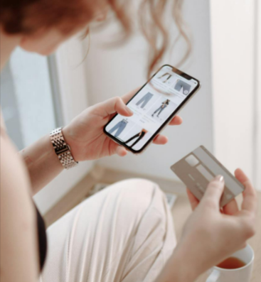 Woman holding cellphone and a credit card while shopping on Footshop