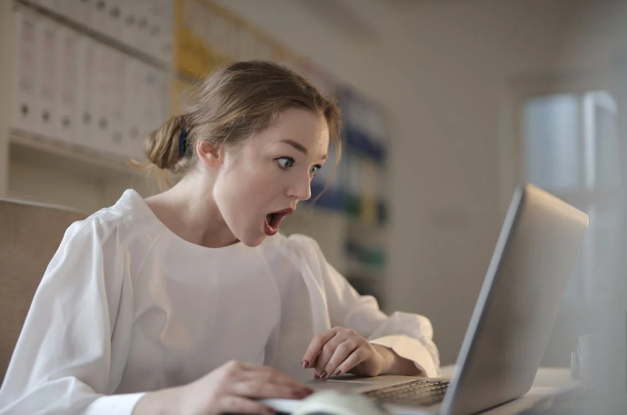 Lady in a white long sleeve shirt using a silver laptop to shop using a River Island student discount