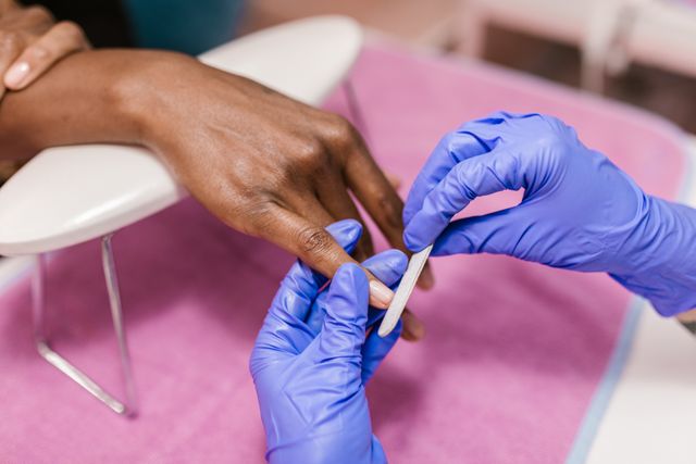 A person receiving a no-polish manicure from a nail technician