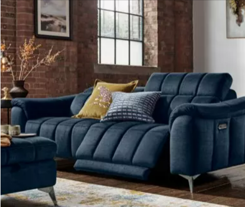 A living room with a dark blue recliner sofa, ottoman and throw pillows from Furniture Village