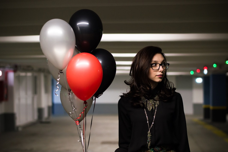 A female student holding balloons  going to collect a cake she bought with a Cake Rush promo code