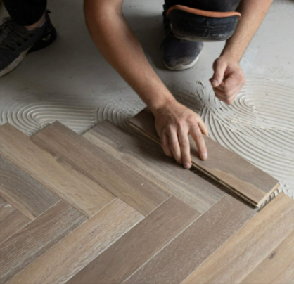 A person laying down wooden tiles from Flooring Surgeons