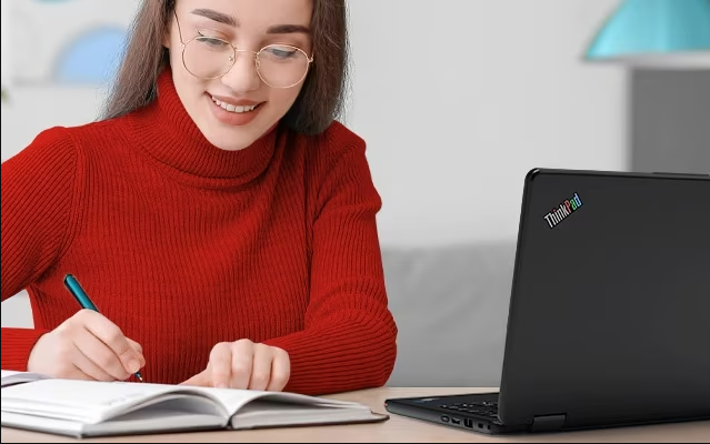 A student coping a Birdsnest promo code from a computer on a book while seated