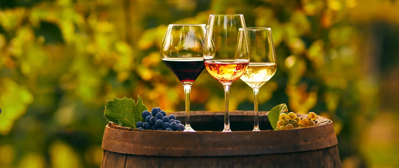 A picture with three wine glasses showing red grapes and white grapes