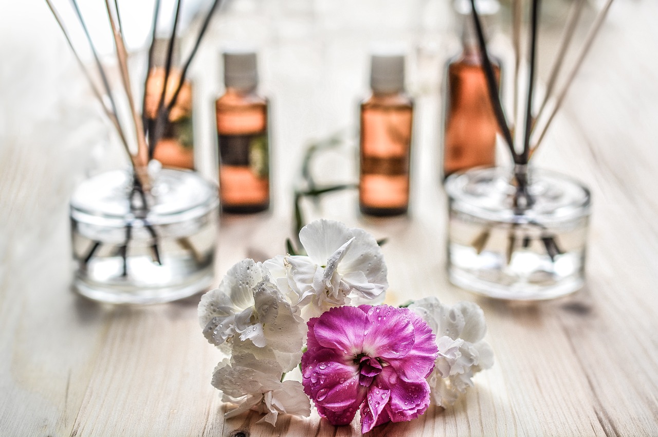 aromas para casa naturales con flores rosas en fondo blanco y botes transparentes