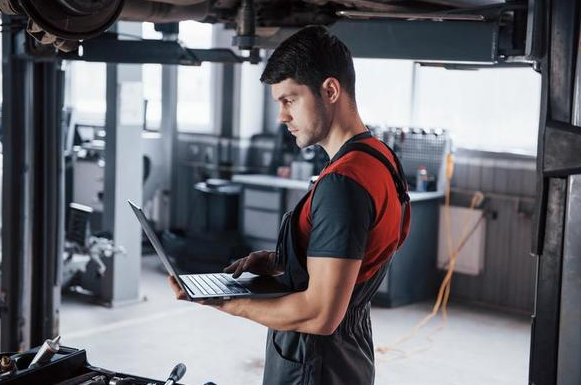 Students at the workshop in uniform looking at a Mobile Tyre Shop promo code on a laptop