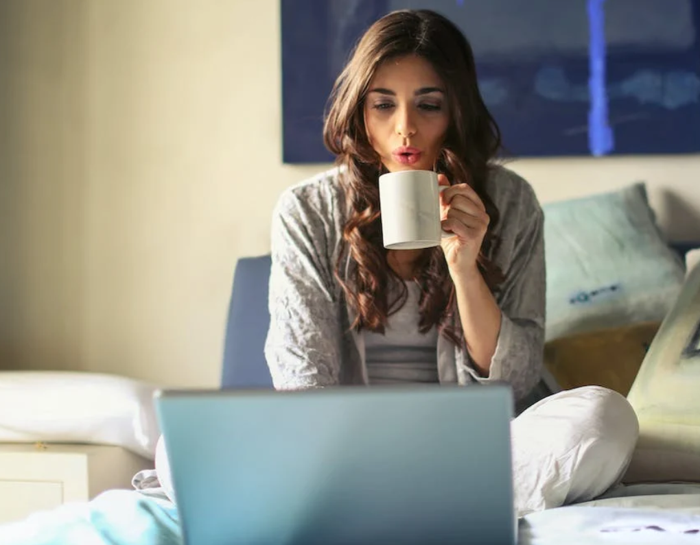 studentessa mentre beve un caffè e cerca un codice sconto Razer sul suo laptop