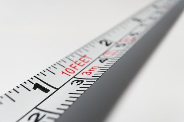 A close-up of a white 10-foot steal measuring tape against a white background.