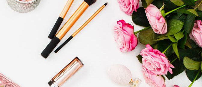 Ein Blumenstrauß neben mehreren Make-Up-Stiften auf weißer Oberfläche