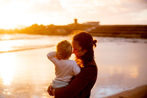 A mother holding her child and watching the sunset