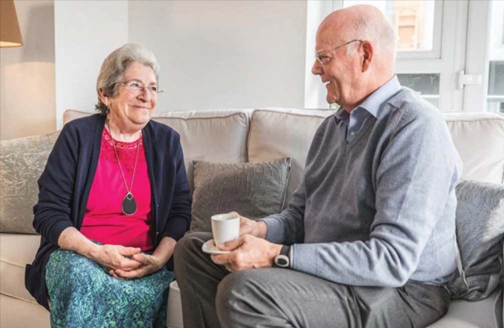 An elderly couple relaxing and chatting over an afternoon tea in the safety of the PPP taking care home monitoring system