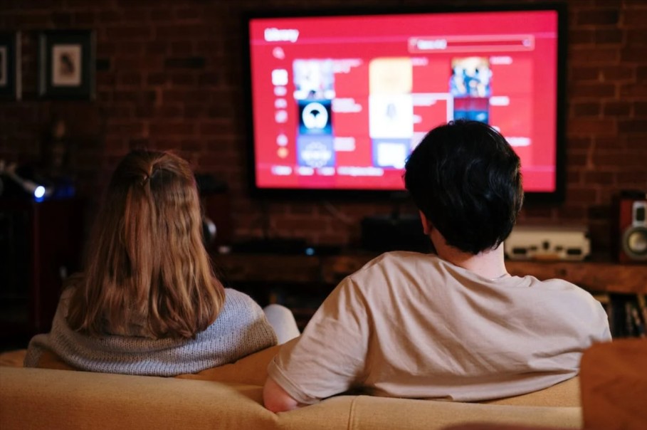 coppia seduta sul divano mentre usa i dispositivi Philips Hue tramite la televisione, acquistati con un promo code Philips Hue