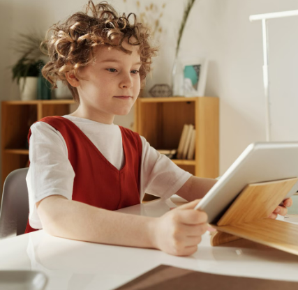 Young child engaged with a refurbished tablet from Grade Mobile for online education at home.