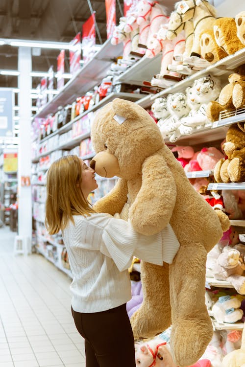 A woman hugging a giant teddy bear in a toy store